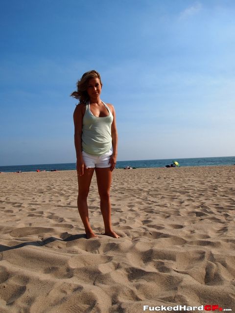 Страстная милашка в белоснежном бикини обнажает свою красоту на песке, показывая лучшие части тела